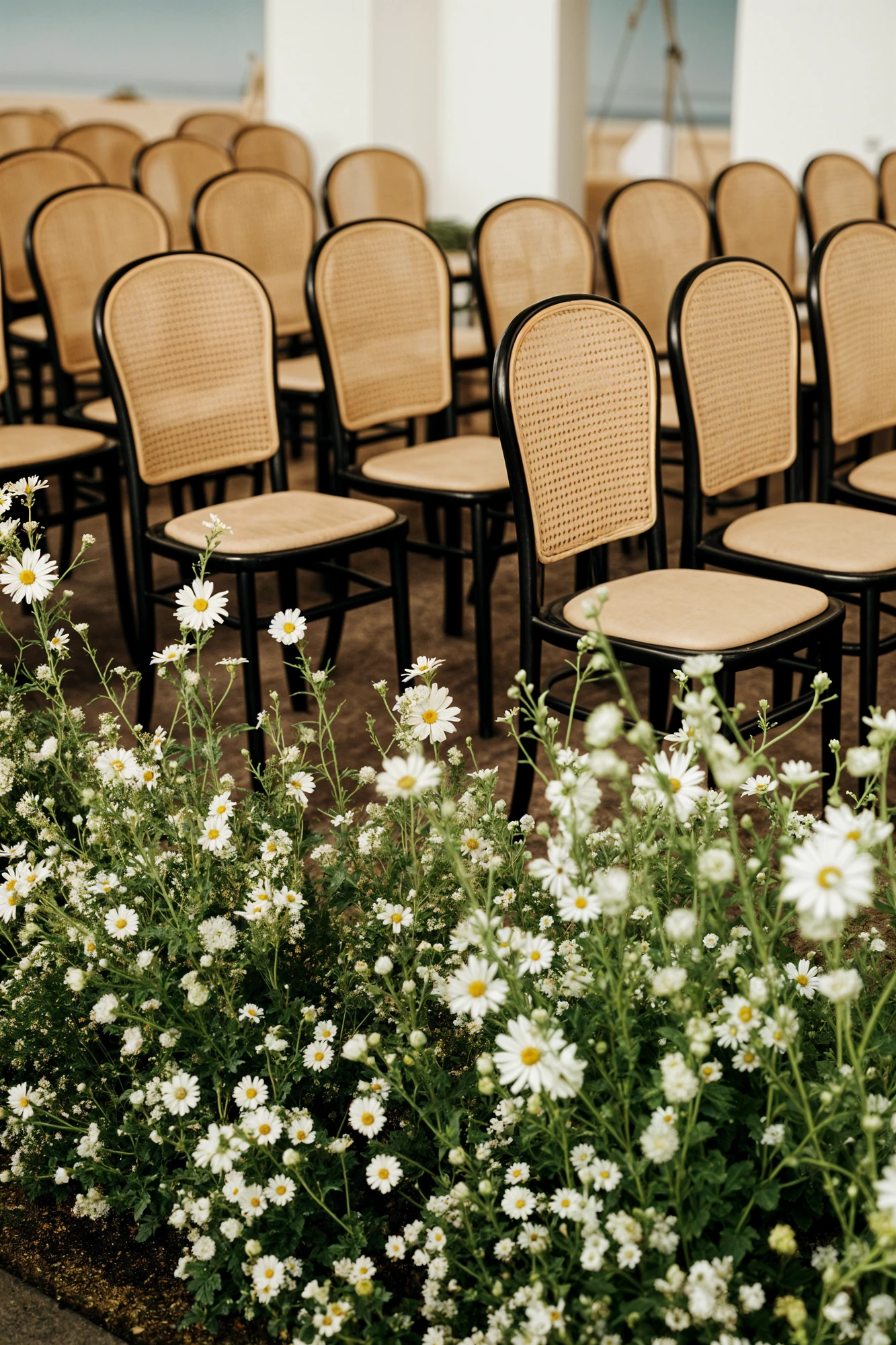 Wicker Wedding Ceremony Seats With Black Trim Next to White Flower Decor