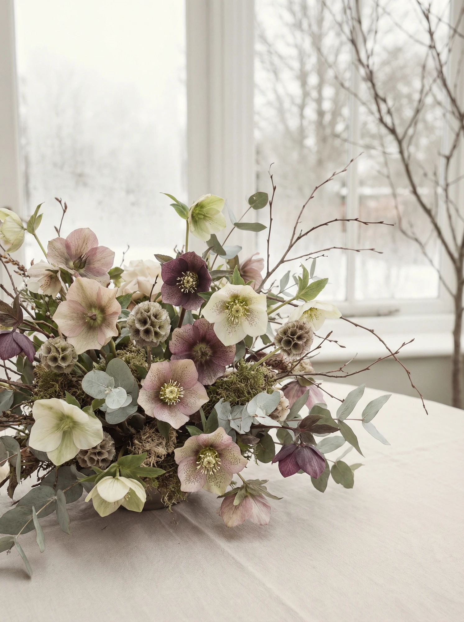 Bride holding a bouquet of hellebore, garden roses, and chocolate cosmos